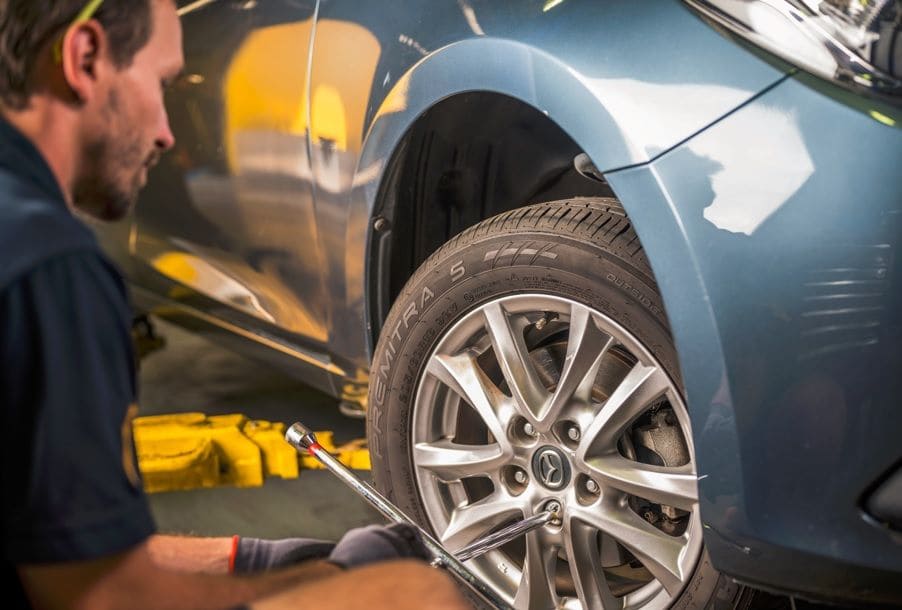 Mechanic inspecting and repairing car brake system on front wheel in workshop