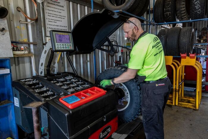 Tyre technician using a wheel balancing machine at a Sunshine Coast workshop