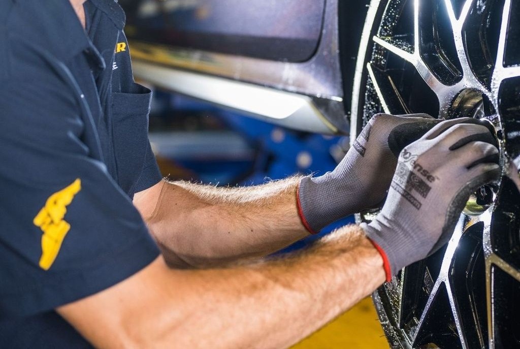 Technician fitting a car wheel during a tyre and brake service