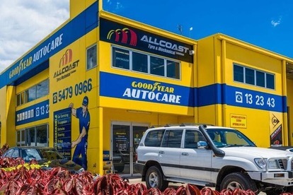 Front view of Allcoast Tyre & Mechanical Goodyear Autocare workshop with visible signage, vehicles, and red shrubs in foreground.