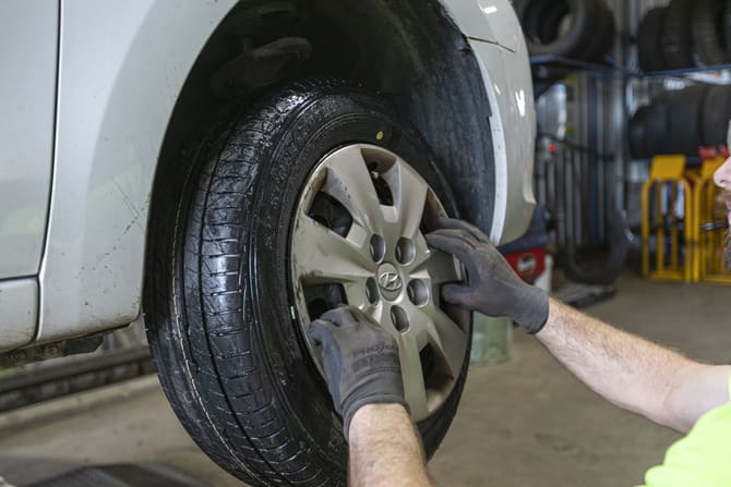 Mechanic fitting a tyre on a car at a tyre workshop
